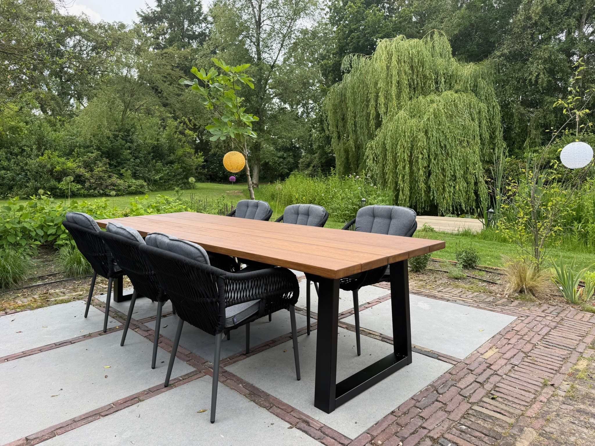 Groene tuin platteland Tuintafel Iroko 300x100cm Grassland Beige Rubio Trapezium 6-8 personen Tuinstoel Pescara zwart
